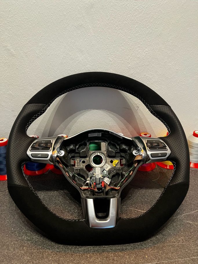 Sportliches Lenkrad mit Bedienelementen und schwarzem Lederbezug.